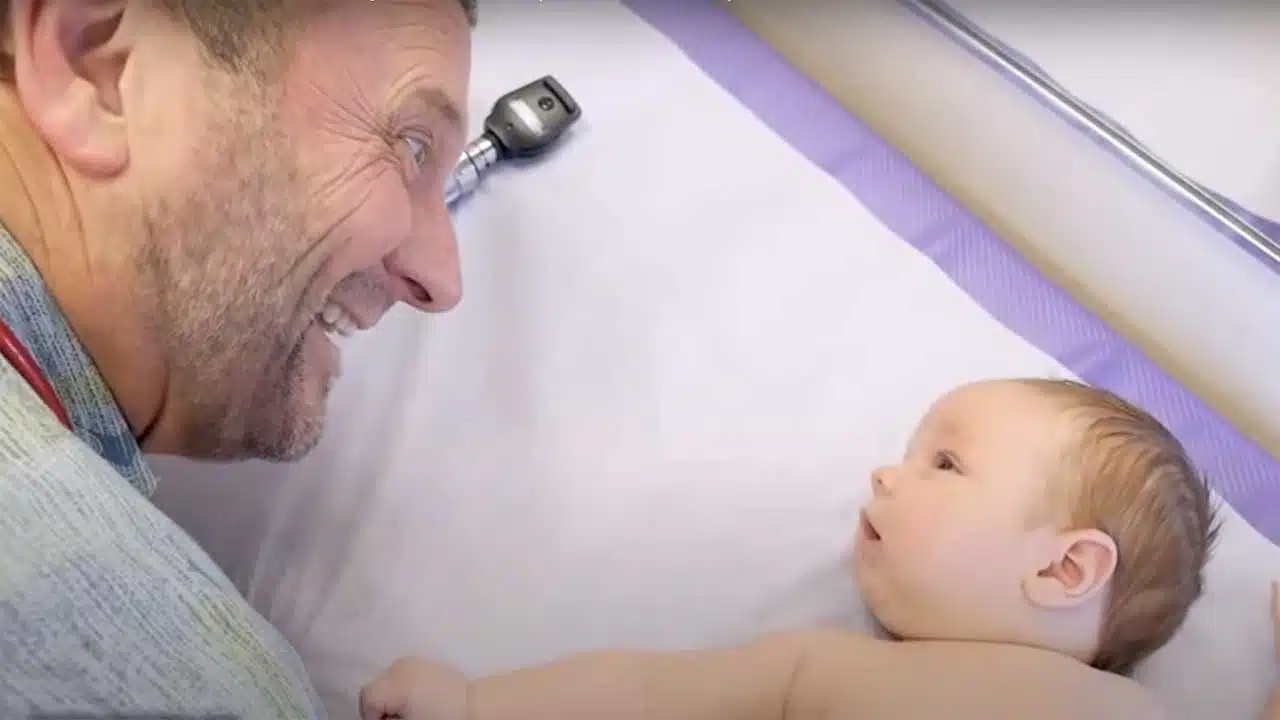 Dr. Paul Thomas works on getting a smile out of a 2-month-old baby (image from "A Crazy Day in the Life of a Busy Pediatrician" on Dr. Paul's YouTube channel).